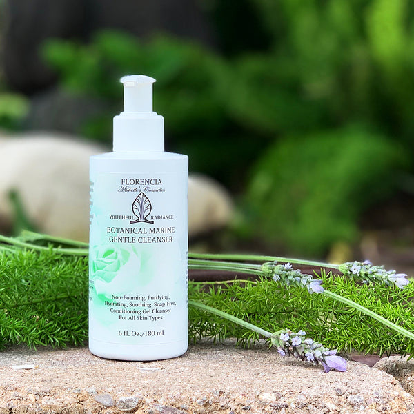 A Botanical Marine Gentle Cleanser bottle with lavender laying behind the bottle on a rock.