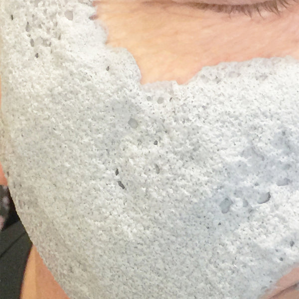 Close up of the White Charcoal O2 Detox Masque on a womans face.