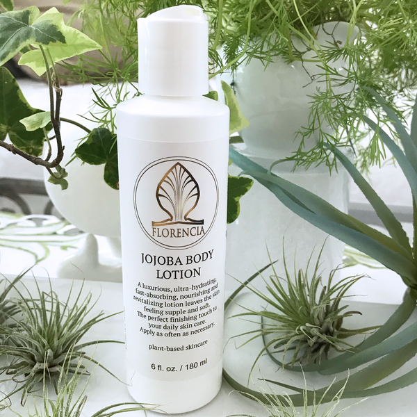 Open bottle of Jojoba Body Lotion by Florencia on the table with green plants